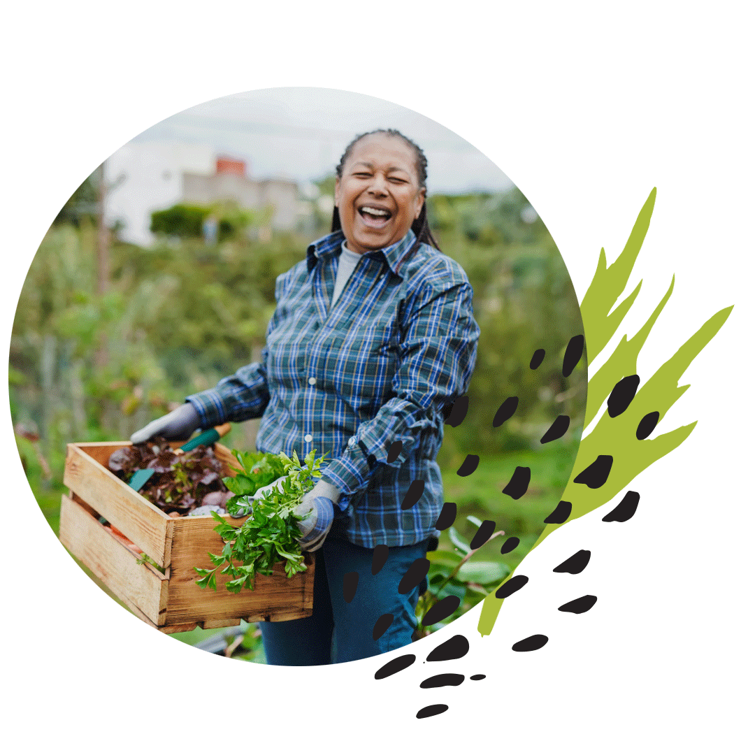 smiling woman in a plaid shirt holding a crate of vegetables in a field