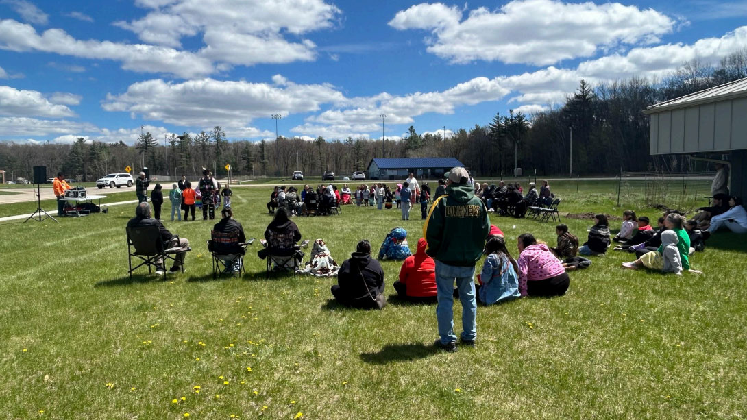 large circle of people sitting outside under blue sky